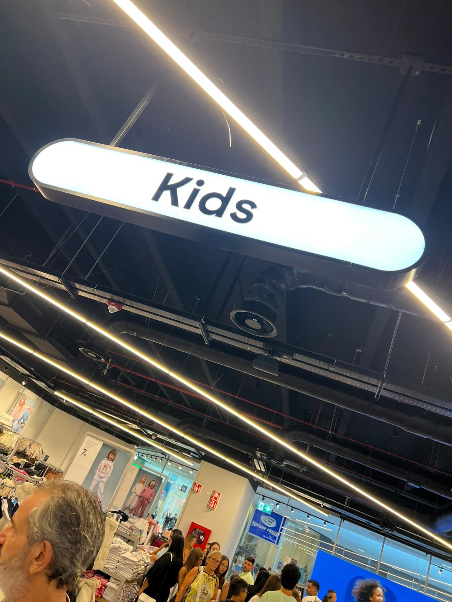 Illuminated Kids department sign suspended above the shop floor