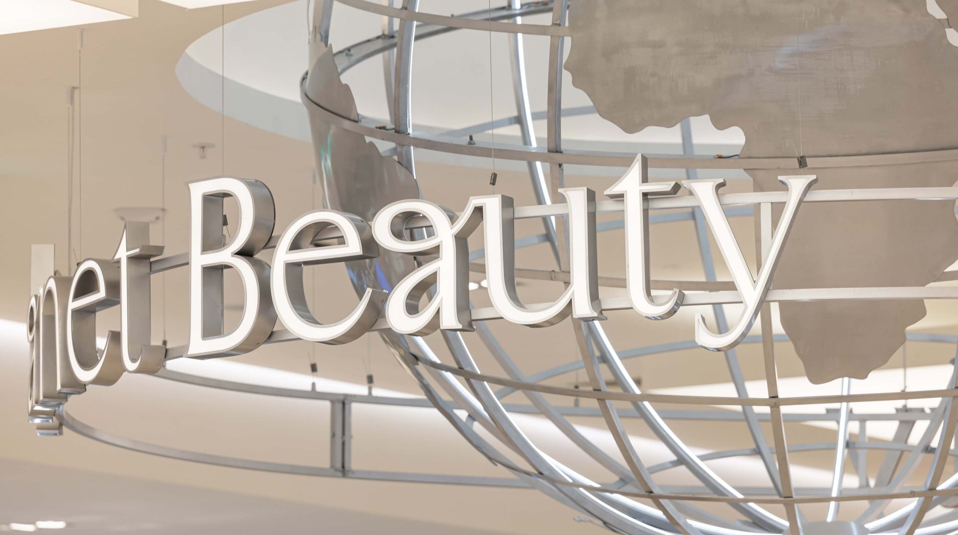 Close-up of the stainless-steel Planet Beauty lettering beneath the aluminium globe